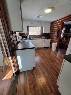 A kitchen with wooden flooring, white cabinets, and a central island. - Fantastic Lakefront Beach House with Stunning Views in St. Ignace, Michigan (St. Ignace)