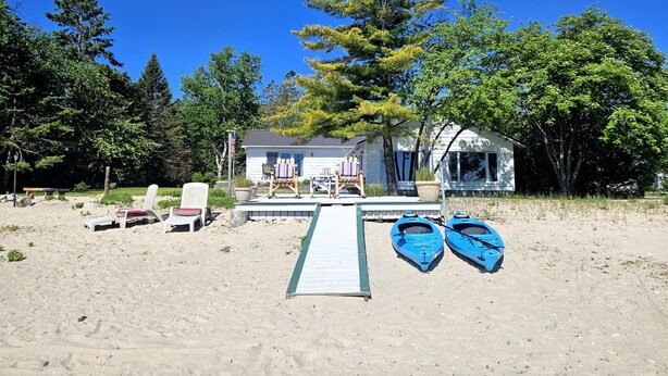 A beach house with a dock, two paddle boats, and beach chairs. - Fantastic Lakefront Beach House with Stunning Views in St. Ignace, Michigan (St. Ignace)