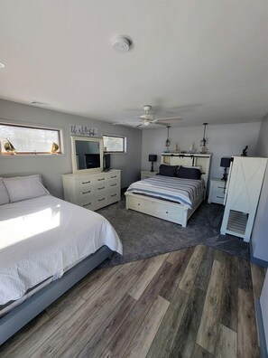 A bedroom with a bed, a dresser, a nightstand, a ceiling fan, and a window.