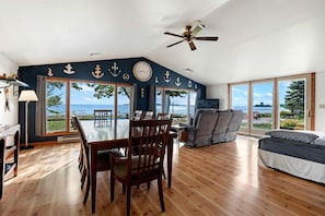 A spacious room with a dining table, chairs, a sofa, and a ceiling fan. - Fantastic Lakefront Beach House with Stunning Views in St. Ignace, Michigan (St. Ignace)
