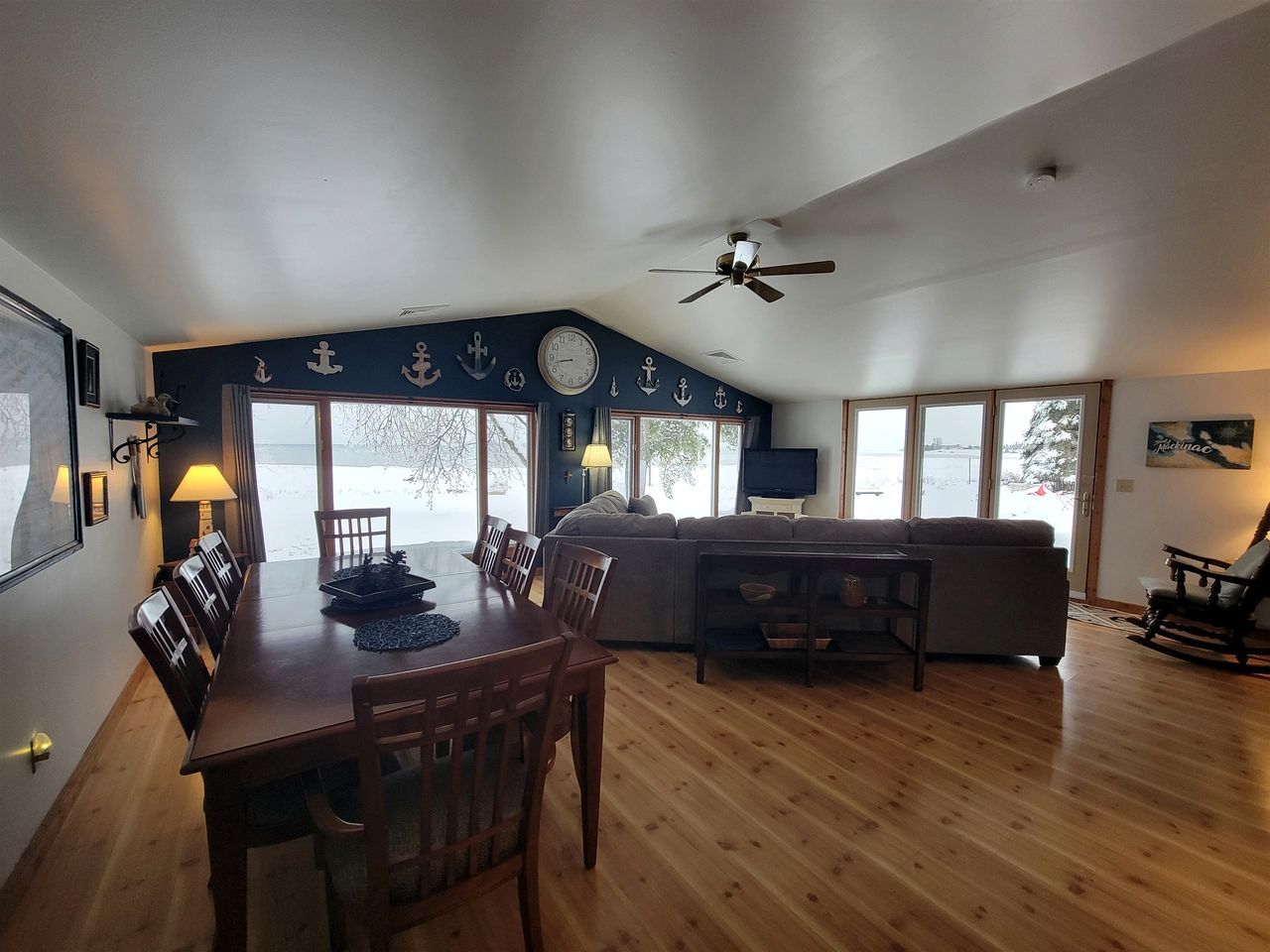 A dining area with a wooden table and chairs, a sofa, and a television.