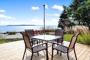 Een terras met tafel en stoelen met uitzicht op het water.