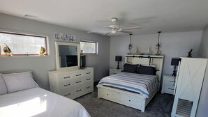 A bedroom with a bed, a dresser, a nightstand, a ceiling fan, and a window. - Fantastic Lakefront Beach House with Stunning Views in St. Ignace, Michigan (St. Ignace)