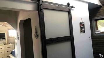 A room with a sliding barn-style door, a small window with a towel, and a sign that says 'LIVE LOVE LAKE.'