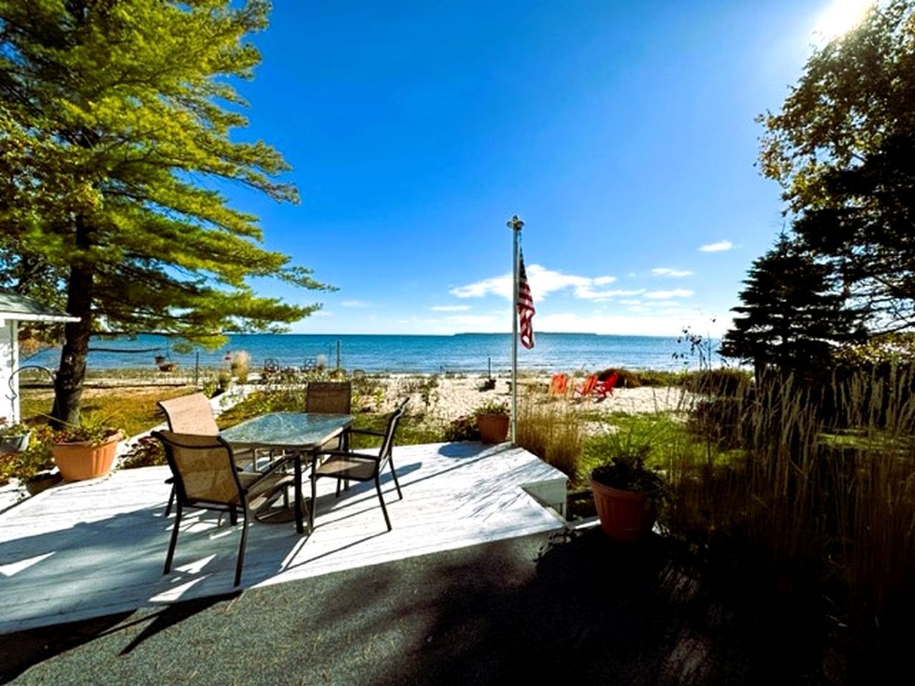 Une terrasse avec une table et des chaises, donnant sur une plage et l’océan.