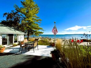 A patio with a table and chairs, an American flag, and a view of the beach.