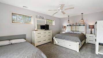 A bedroom with a bed, dresser, vanity, and a ceiling fan.