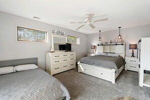 A bedroom with a bed, dresser, vanity, and a ceiling fan.
