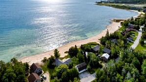 A coastal residential area with houses along the beachfront, clear skies, and calm waters. - Fantastic Lakefront Beach House with Stunning Views in St. Ignace, Michigan (St. Ignace)