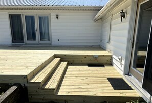 A wooden deck with a ramp leading to a sliding glass door. - Fantastic Lakefront Beach House with Stunning Views in St. Ignace, Michigan (St. Ignace)
