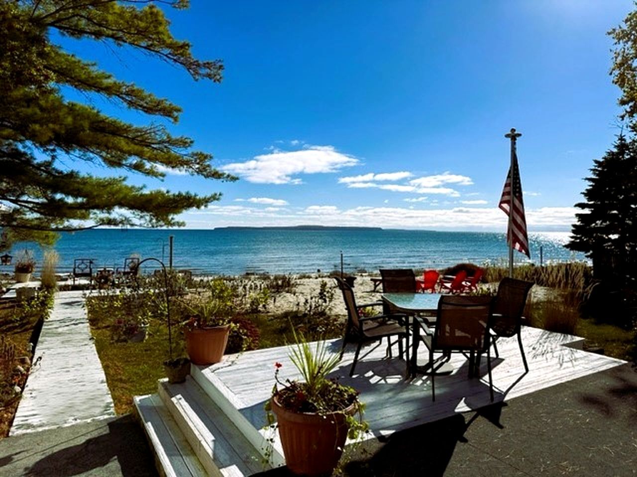 A deck with outdoor seating, a flag, and a view of the ocean.