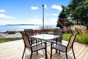 A deck with a table and chairs overlooking a body of water. - Fantastic Lakefront Beach House with Stunning Views in St. Ignace, Michigan (St. Ignace)