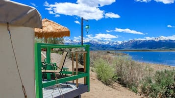 A beachside structure with a thatched roof, a green frame, and a bench.