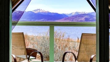A wooden deck with two chairs facing a scenic view of mountains and a body of water.