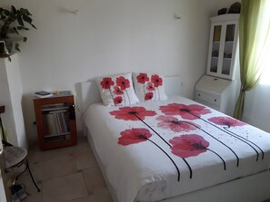 A bedroom with a bed, a nightstand, a cabinet, a chair, and a bookshelf.