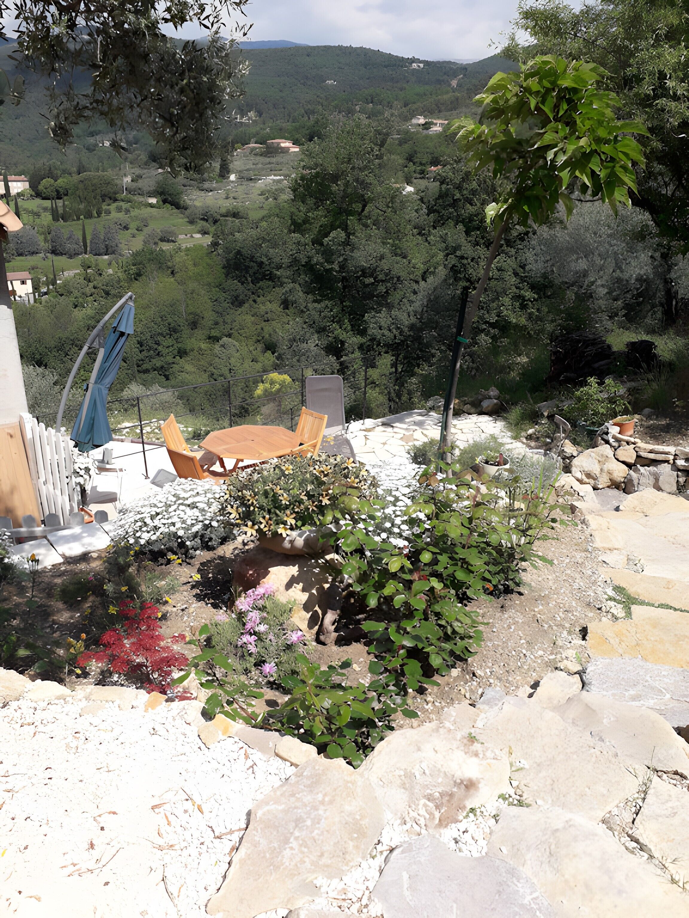 Une terrasse avec des meubles d’extérieur, un chemin de pierres et un jardin agrémenté de différentes plantes.. Chambre d’hôtes « Charmante chambre double dans villa » avec vue montagne, Wi-Fi, climatisation