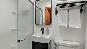 Un baño con un lavamanos blanco, un espejo, un inodoro y un perchero para toallas.