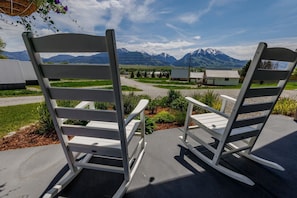 Two white rocking chairs with a mountainous landscape in the background.