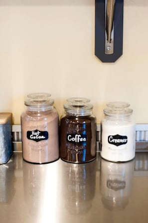 Three glass jars labeled 'Hot Cocoa,' 'Coffee,' and 'Creamer' on a countertop.