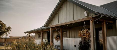 A building with a covered porch, a sloped roof, and hanging flower baskets.