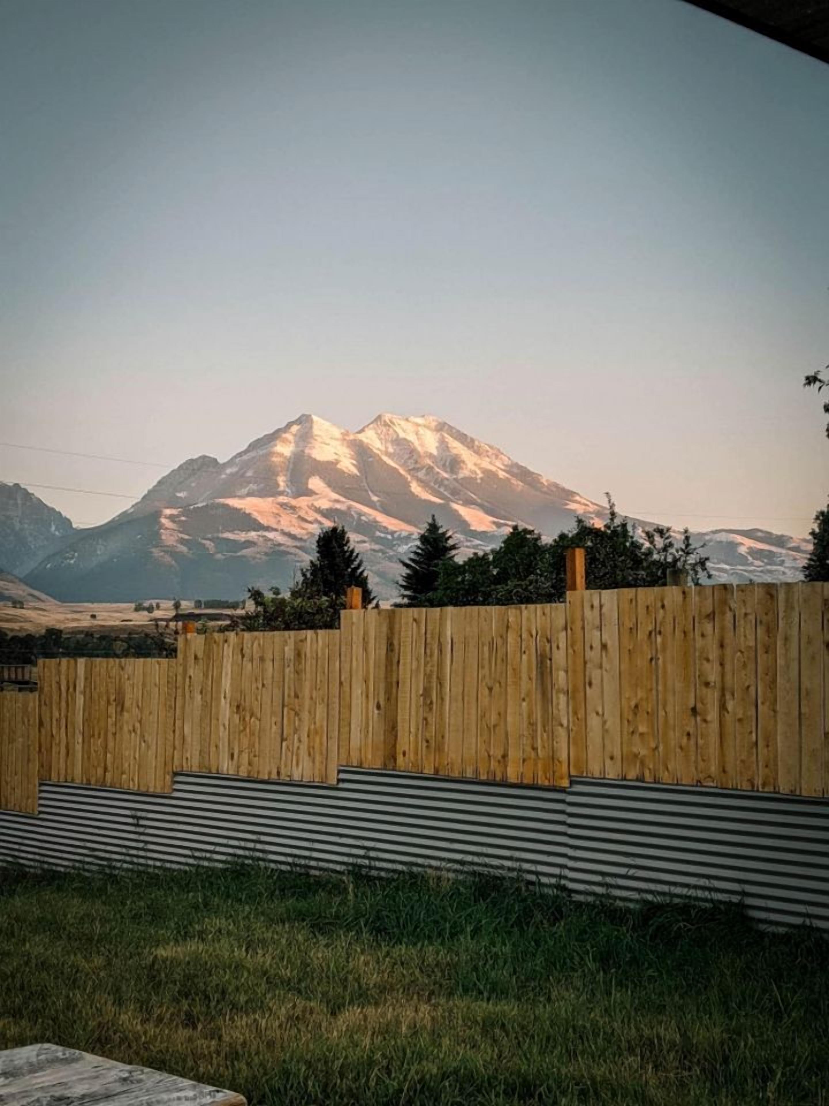 Ein Holzzaun, ein Metallgeländer und ein Berg im Hintergrund.