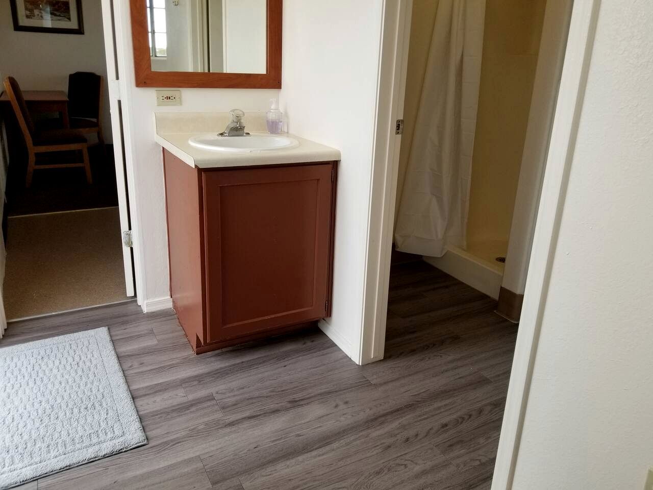 A bathroom with a wooden vanity, a mirror, and a white sink.