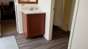 A bathroom with a wooden vanity, a mirror, and a white sink.