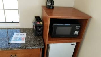 A kitchen with a microwave, a coffee maker, and a refrigerator.