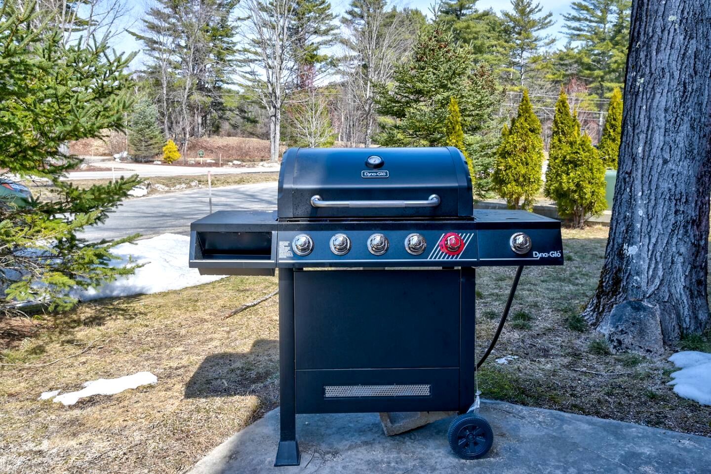 Una parrilla exterior negra con cuatro perillas de control, un estante lateral y un logotipo.
