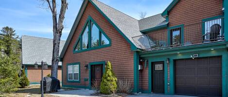 A two-story house with a garage, a balcony, and a well-maintained lawn.