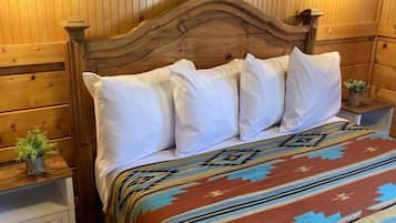 A wooden-paneled room with a bed, two bedside tables, and a wall-mounted painting.
