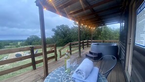 Una terraza de madera con una mesa, sillas, una botella de vino y una toalla.