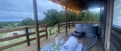 Eine Holzterrasse mit Tisch, Stühlen, einer Weinflasche und einem Handtuch.