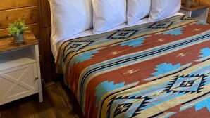 Una habitación con paneles de madera, una cama, dos mesitas de noche y un cuadro colgado en la pared.