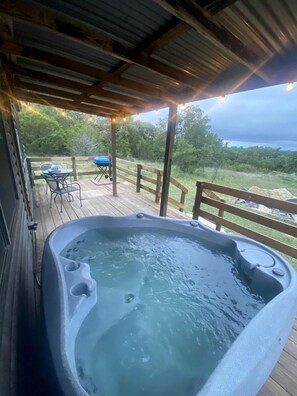 A hot tub on a wooden deck with a view of the surrounding landscape.