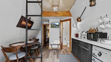 Eine kompakte Küche mit Essbereich, Holzmöbeln und Blick ins angrenzende Badezimmer.