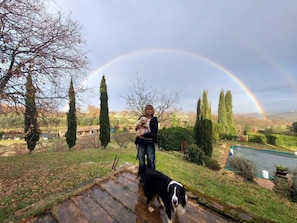 A person holding a child and a dog in a garden with a rainbow in the background. - Laquilaelulivo (Chianciano Terme)