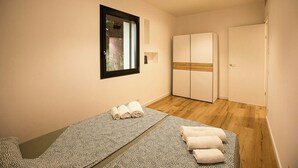 Un dormitorio con cama, armario, espejo y ventana.