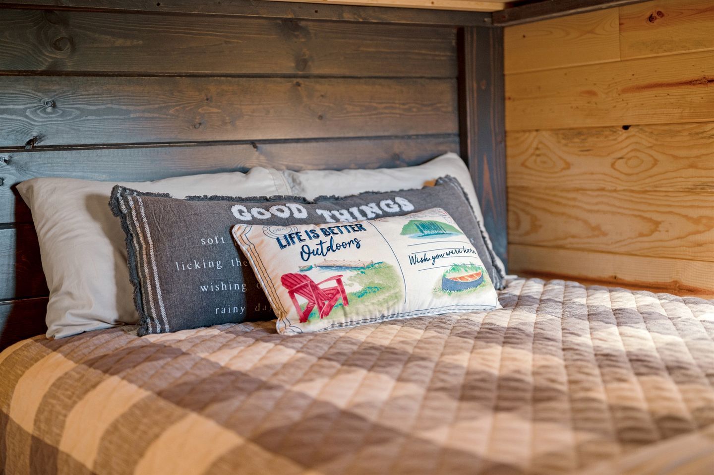 A bed with a quilted blanket, two pillows, and a headboard.
