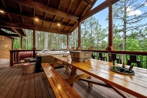 Eine Holzterrasse mit Whirlpool, Picknicktisch und Sitzgelegenheit im Freien.