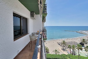 Un balcon avec vue sur la mer, une table avec des chaises et une fenêtre.