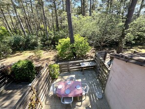 Eine Terrasse mit Tisch für zwei Personen, umgeben von einem Holzzaun, mit einem bewaldeten Bereich im Hintergrund.