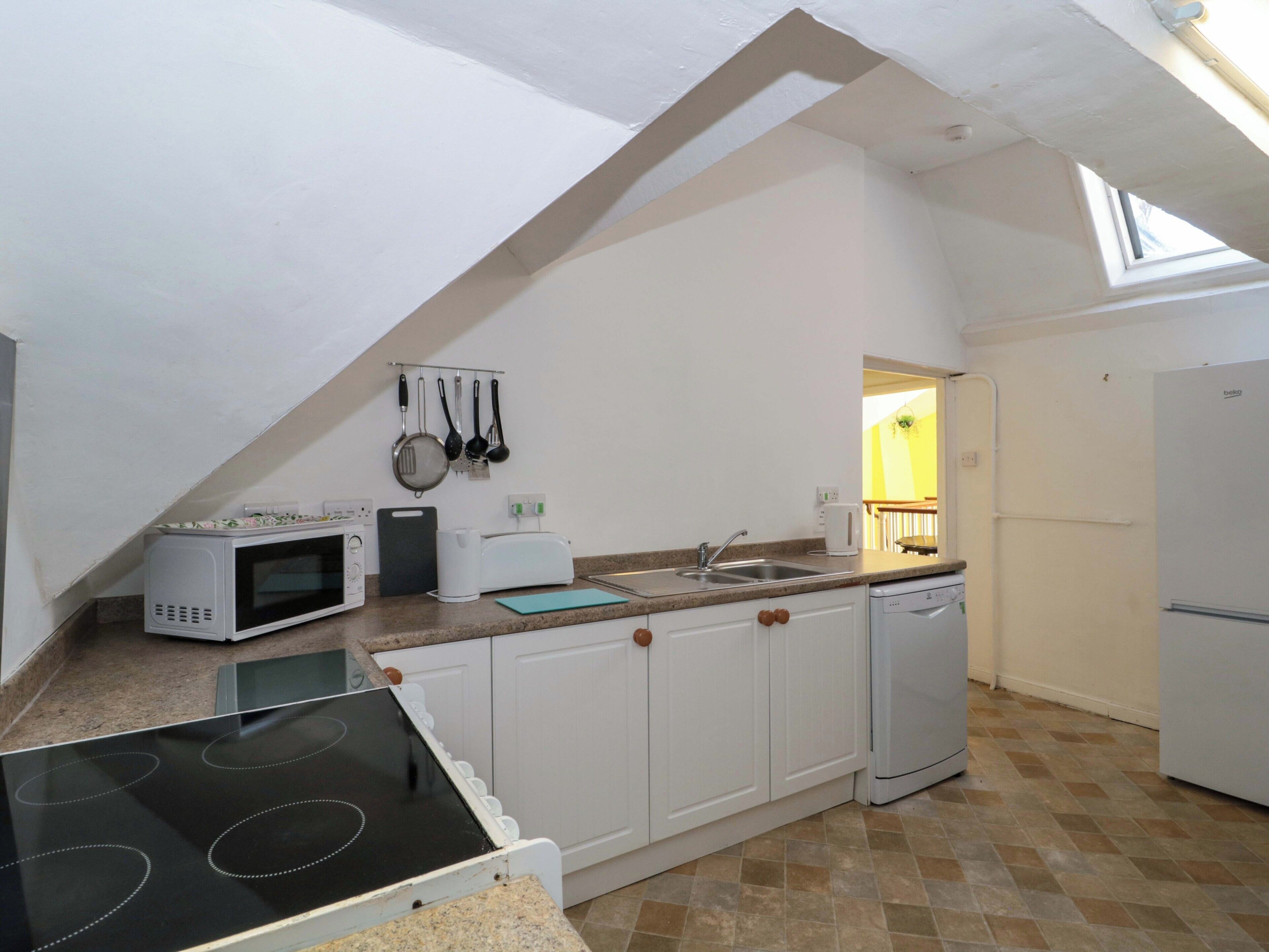 Een keuken met een magnetron, broodrooster, spoelbak en fornuis.