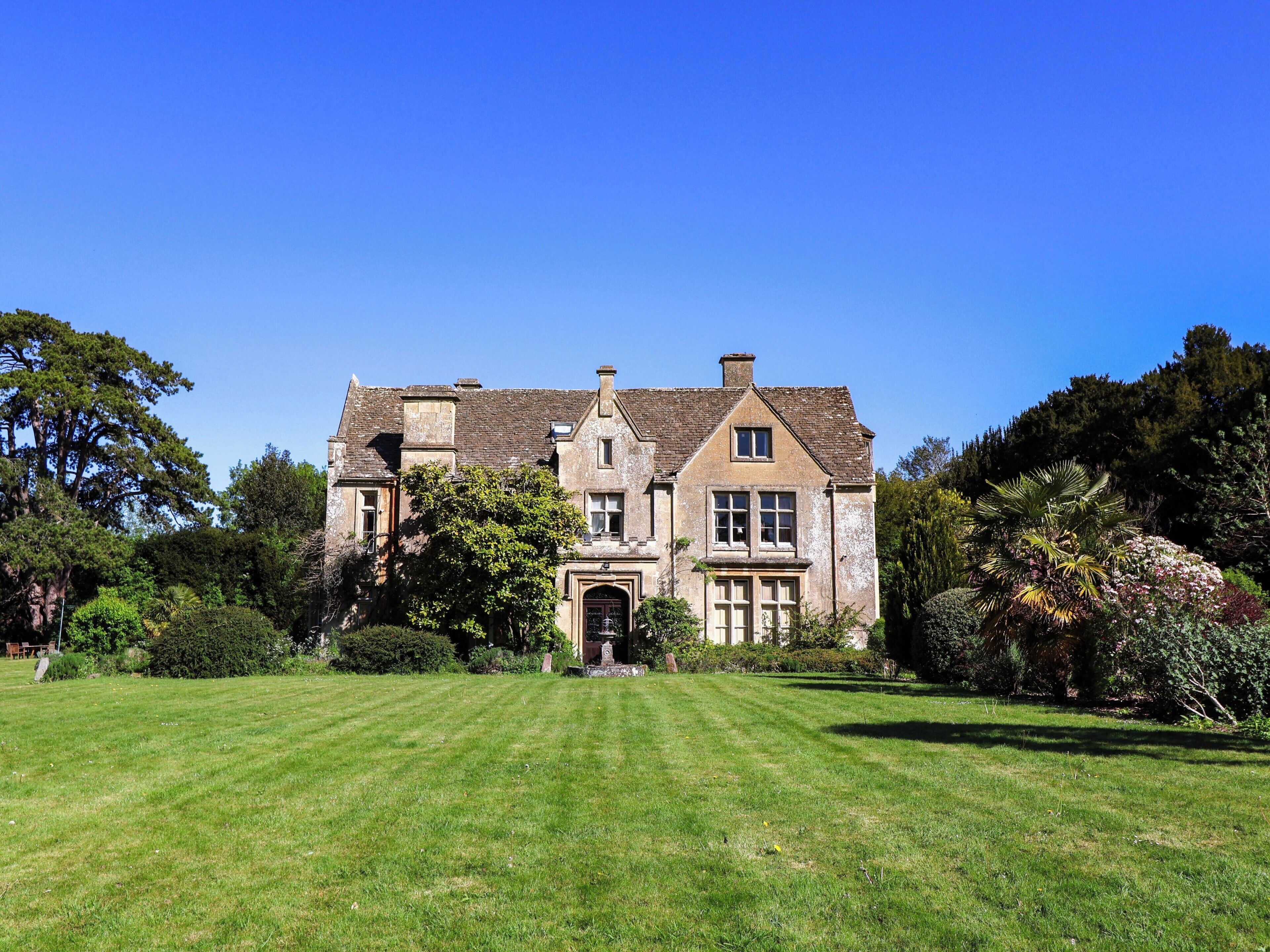 A large, historic building with a symmetrical facade, a central entrance, and a well-maintained lawn in front.