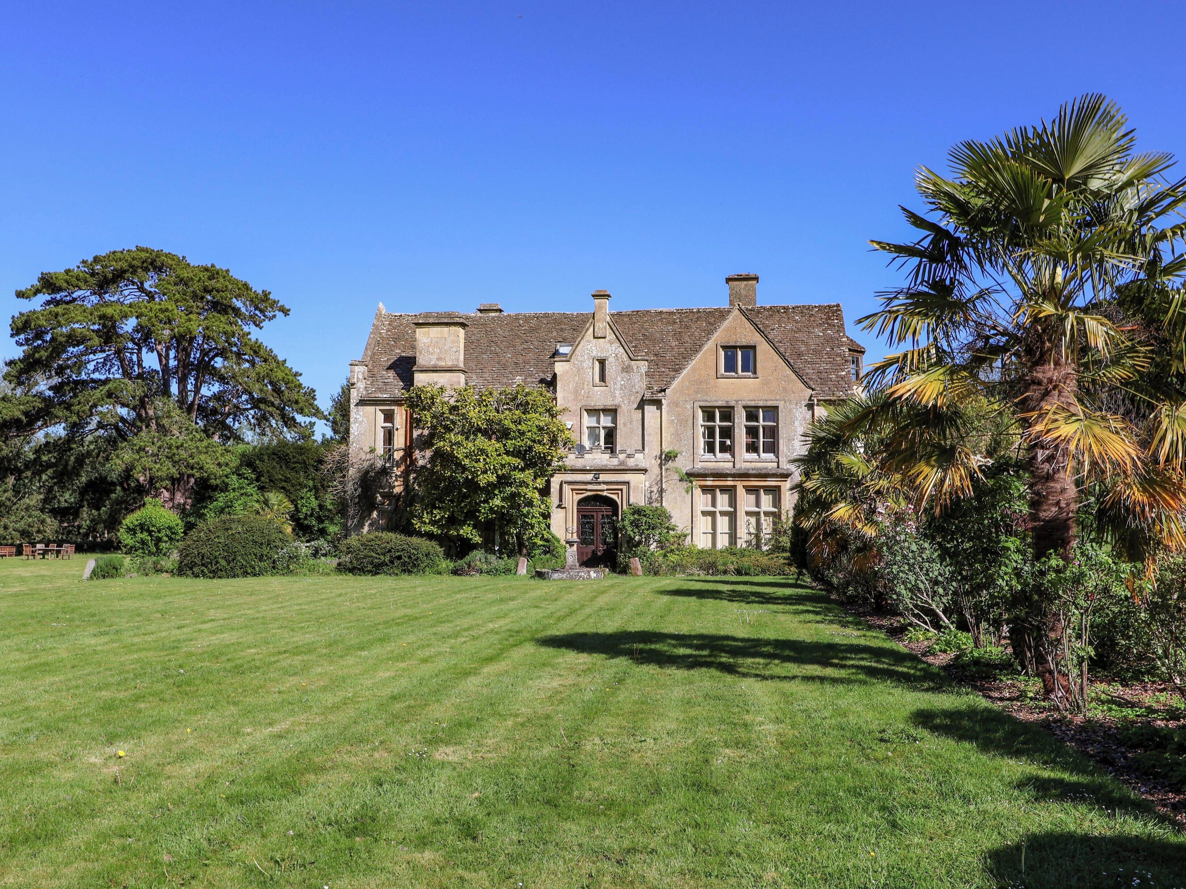 A large, historic building with a well-maintained lawn and mature trees.