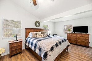 A bedroom with a wooden bed, a dresser, a TV, and a window with blinds. - Chic Cabin with Game Space, Jacuzzi and Private Deck in Tennessee (Speedwell)