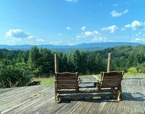 Two wooden chairs on a wooden deck with a view of a forest and mountains in the background. - Chic Cabin with Game Space, Jacuzzi and Private Deck in Tennessee (Speedwell)