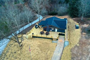 A large house with a deck, a covered outdoor area, and a flag. - Chic Cabin with Game Space, Jacuzzi and Private Deck in Tennessee (Speedwell)