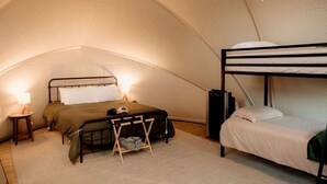 Eine Zelthütte mit Etagenbett, Einzelbett, kleinem Tisch mit Lampe und Lautsprecher.