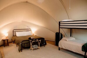 Eine Zelthütte mit Etagenbett, Einzelbett, kleinem Tisch mit Lampe und Lautsprecher.